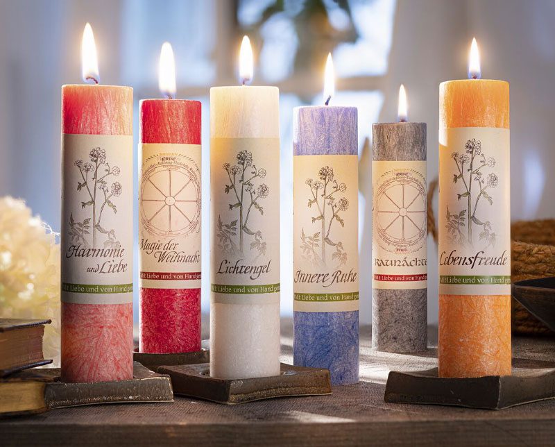 Zes verschillende kruidenkaarsen staan brandend op tafel. 