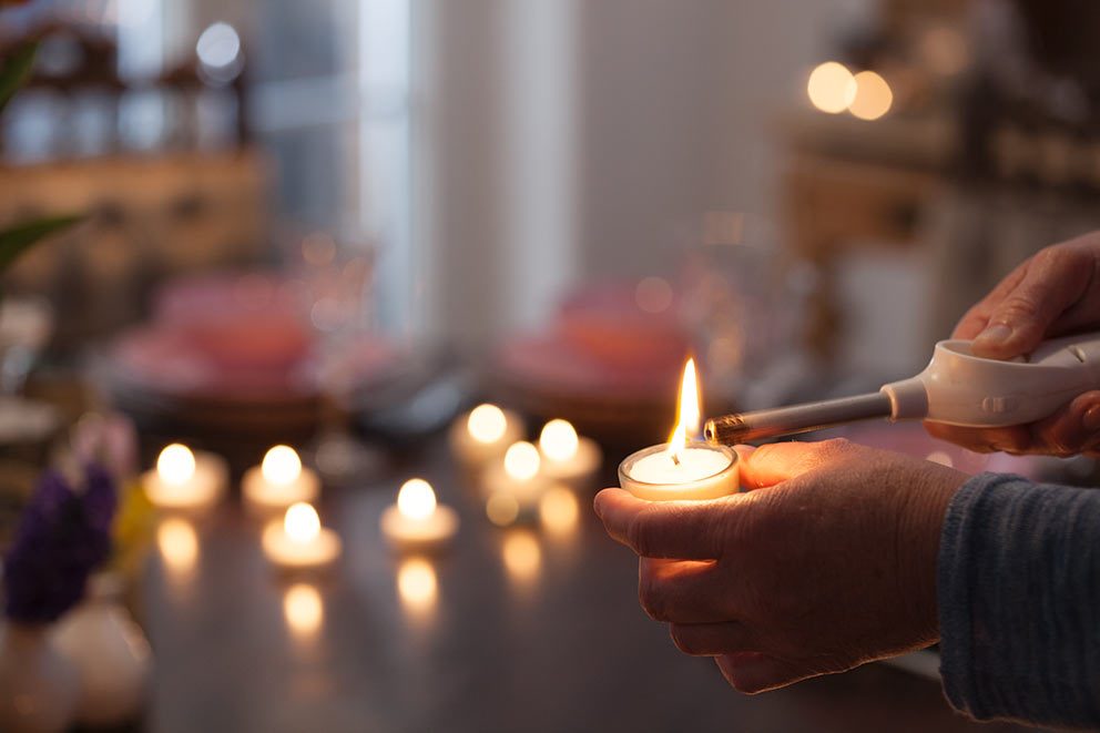 Een eco-theelichtje in een glazen houder wordt aangestoken