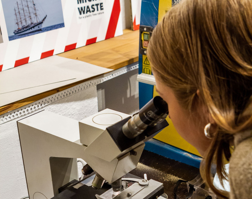 Een vrouw kijkt in een microscoop