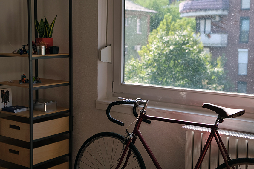 Een racefiets staat voor de radiator bij een raam.