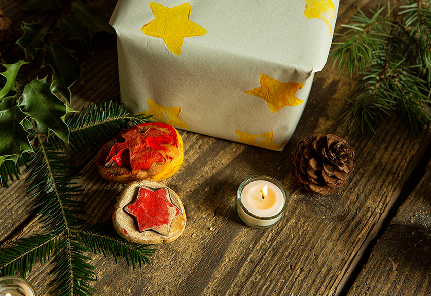Twee aardappelstempels liggen voor een ingepakt cadeau dat met de stempels is versierd.