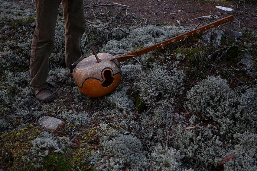 Die selbst gebaute N'goni liegt auf dem Boden in einer wilden Landschaft.