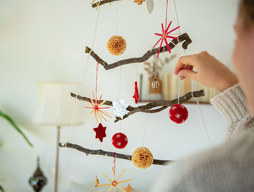 De kerstboom van takken wordt versierd.