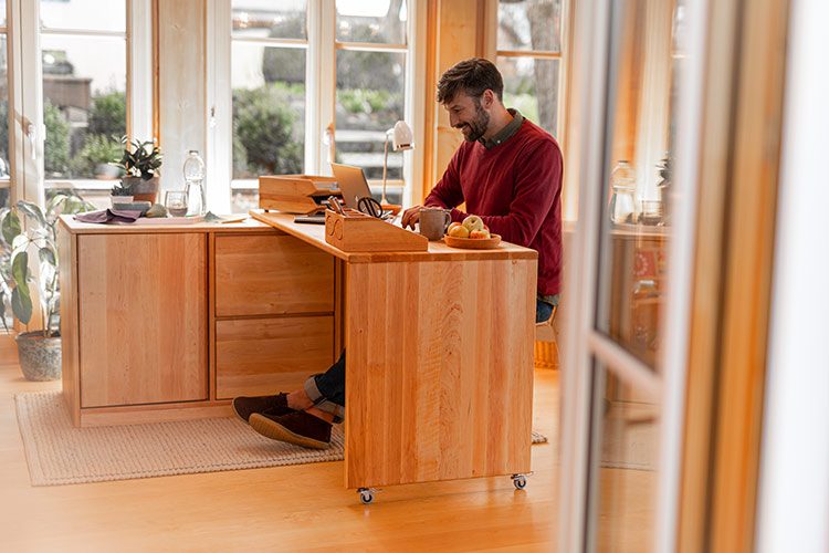 Ein Vater sitzt an einem Holzschreibtisch im Homeoffice.