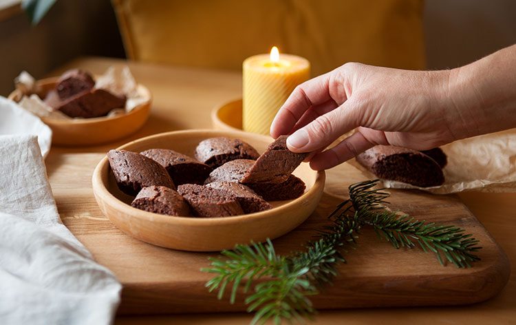 Eine Hand greift sich veganes Magenbrot aus einer Holzschale.