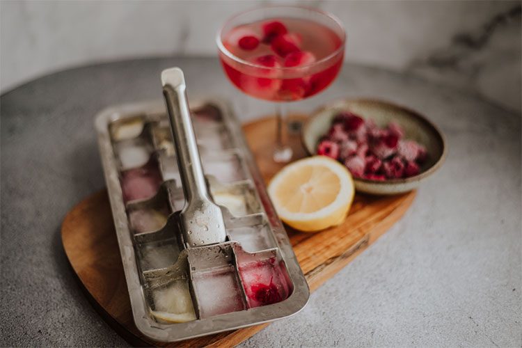 Die Eiswürfelform aus Edelstahl ist mit Eiswürfeln mit Früchten befüllt. 